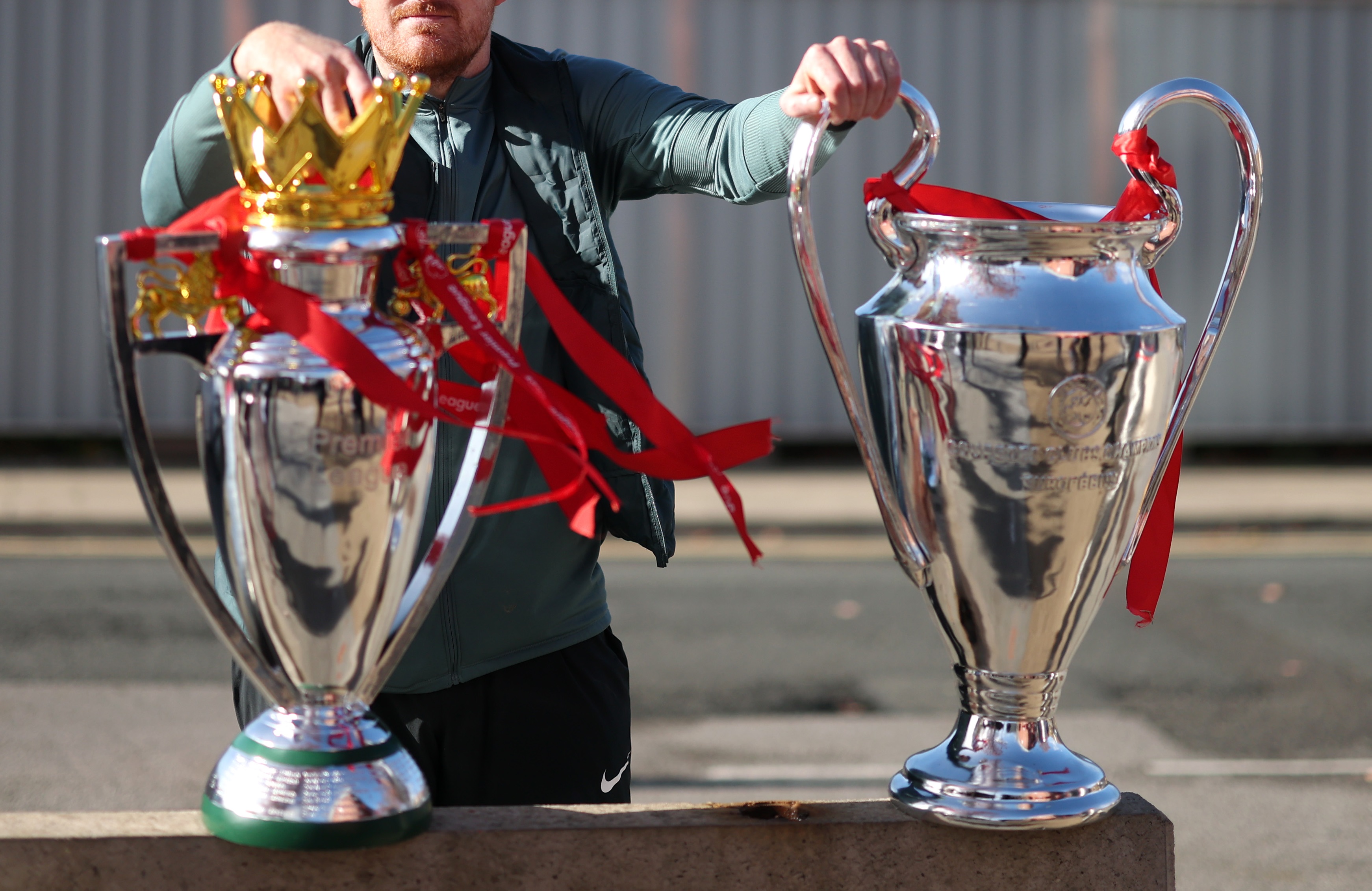 Liverpool fan with replicas of Premier League and Champions League trophies.
