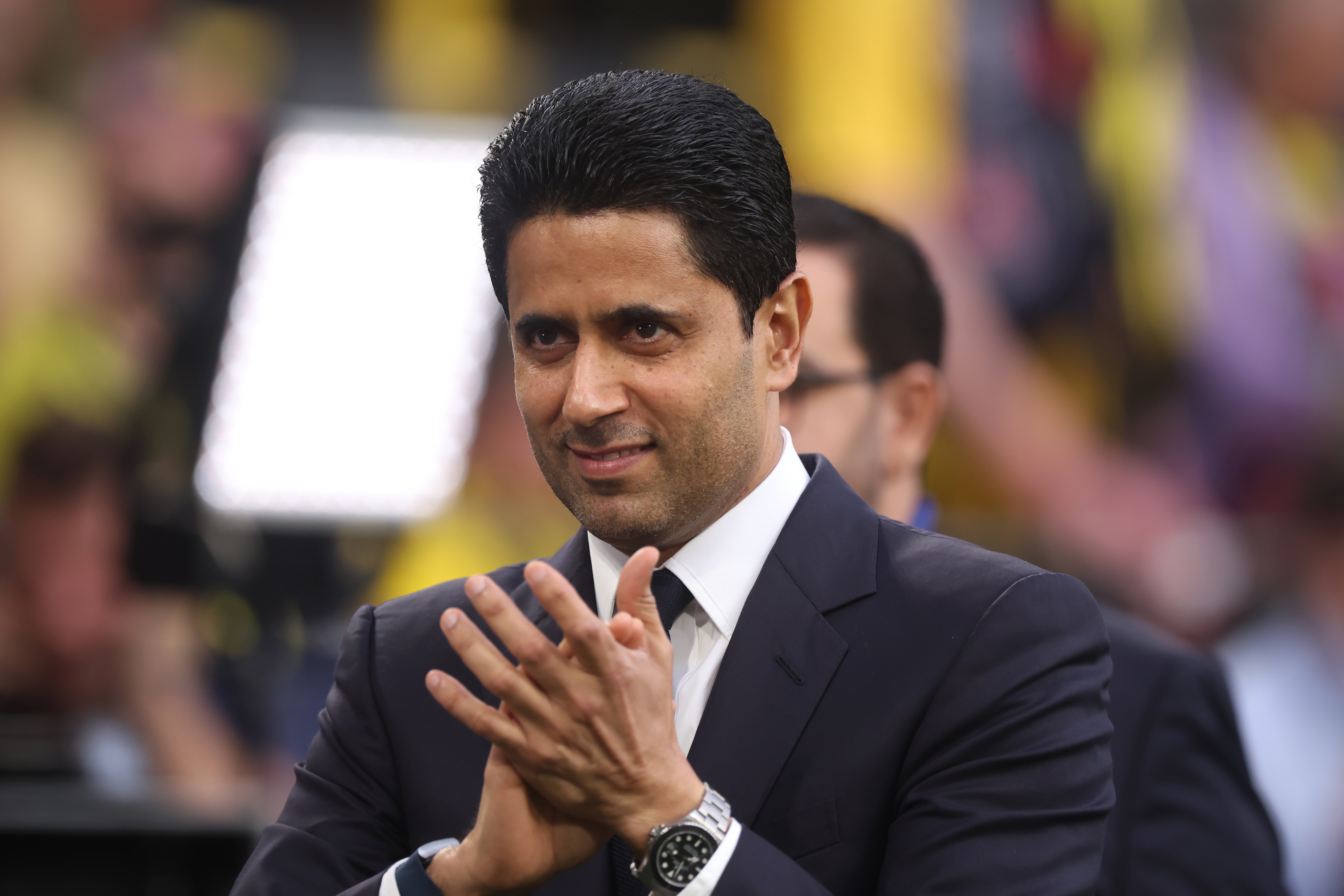 PSG president Nasser Al-Khelaifi applauds fans in Champions League game.