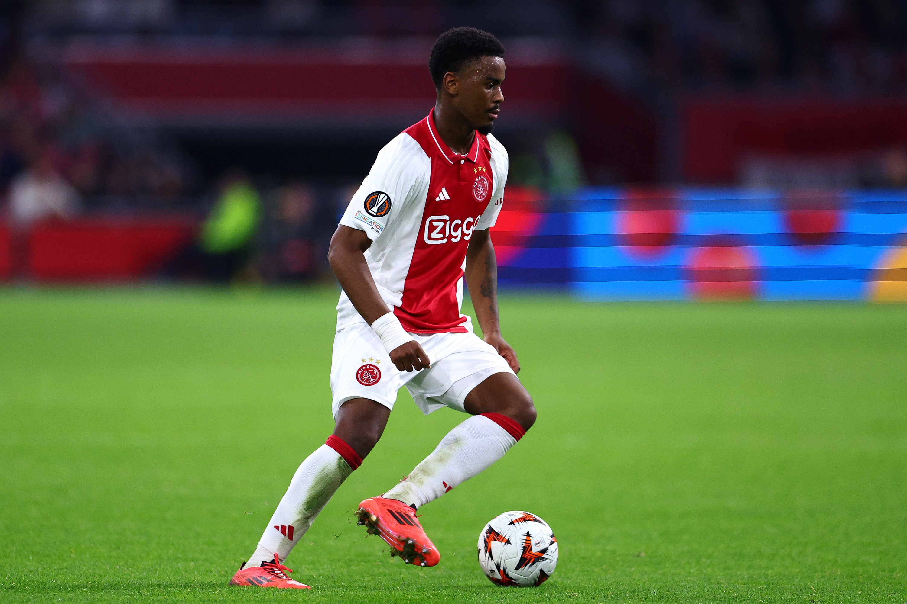 Jorrel Hato dribbles with the ball during an Ajax game.