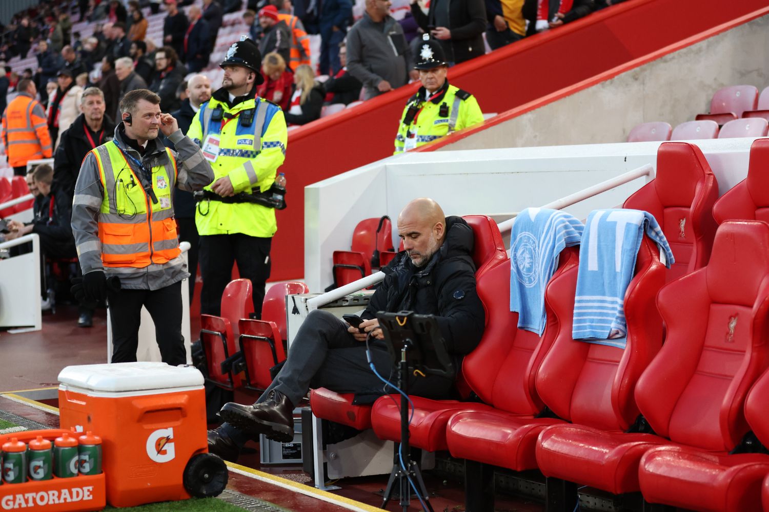 Pep Guardiola sitting on the bench at Anfield