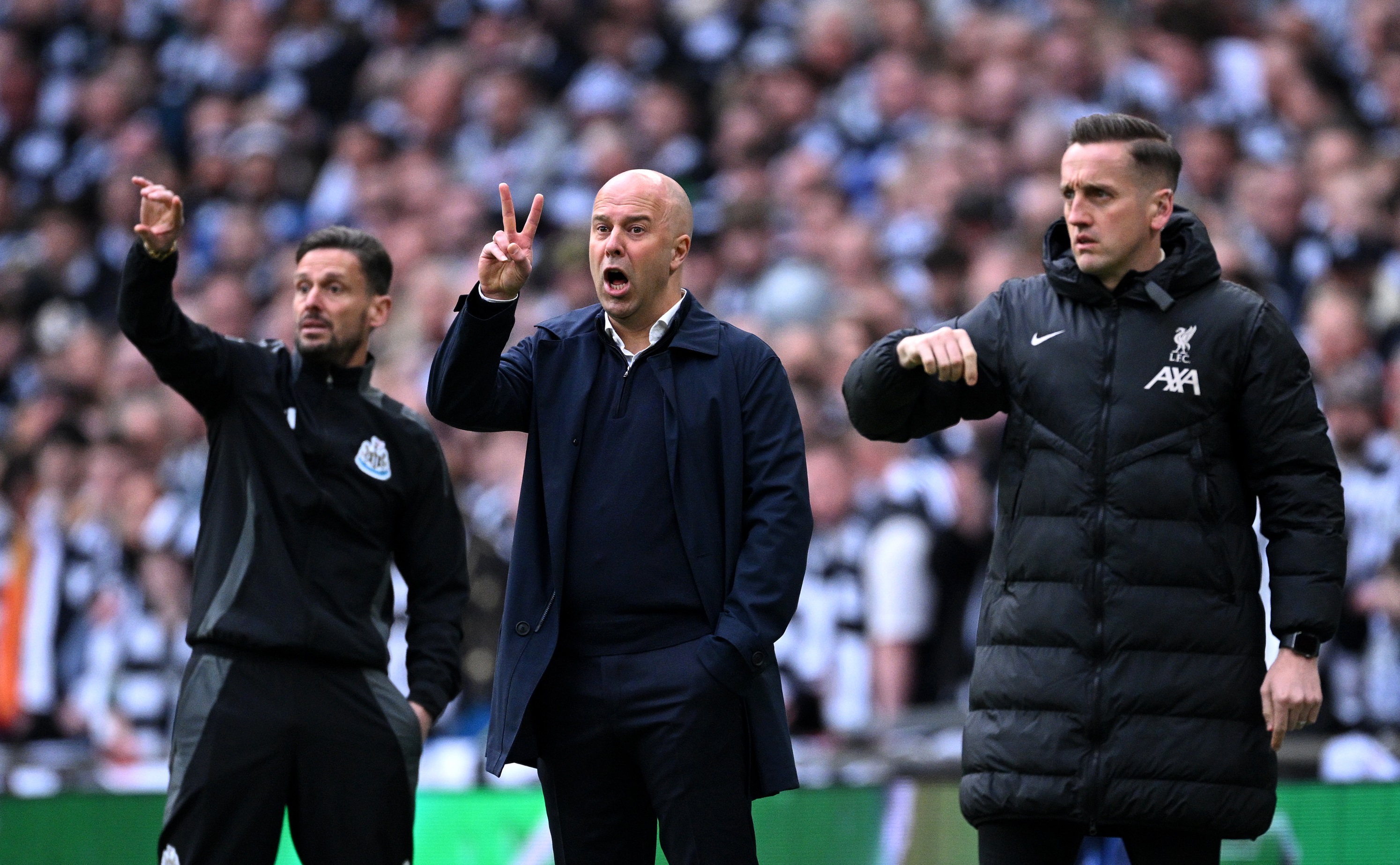 Liverpool head coach Arne Slot holds up two fingers in a v-sign.