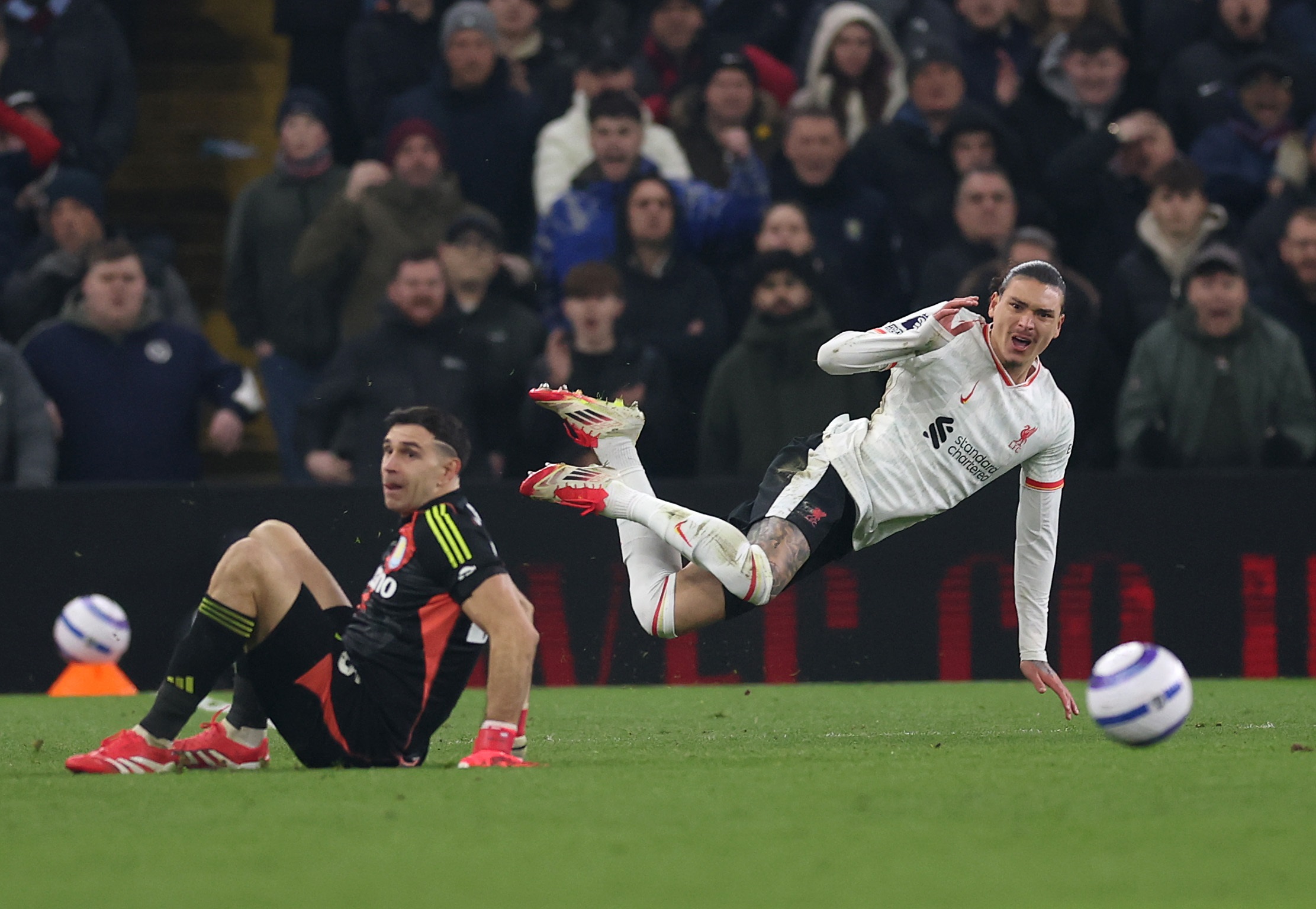 Darwin Nunez falls after being caught by Aston Villa goalkeeper Emi Martinez.