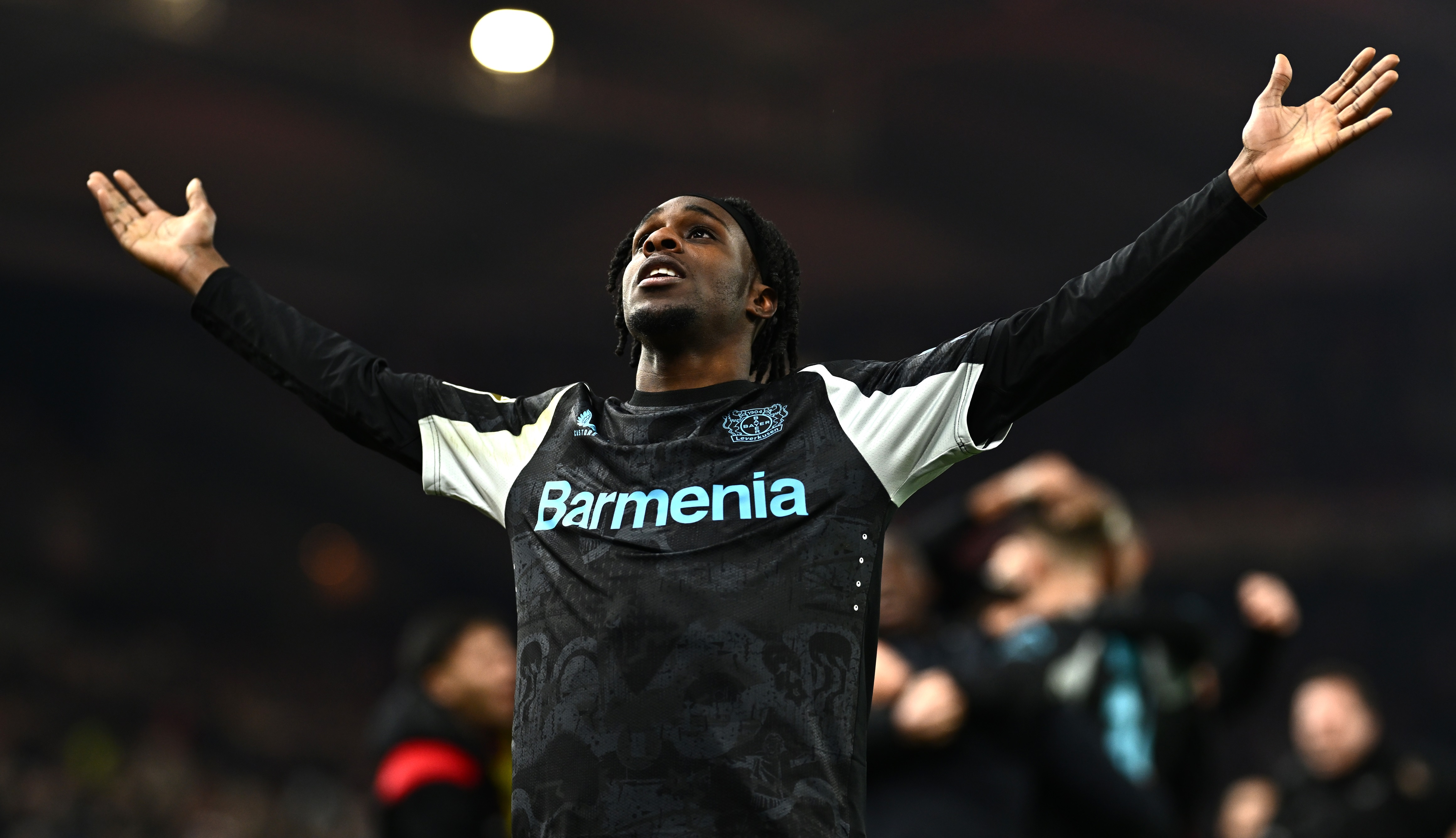 Bayer Leverkusen defender Jeremie Frimpong holds out his arms wide in celebration.