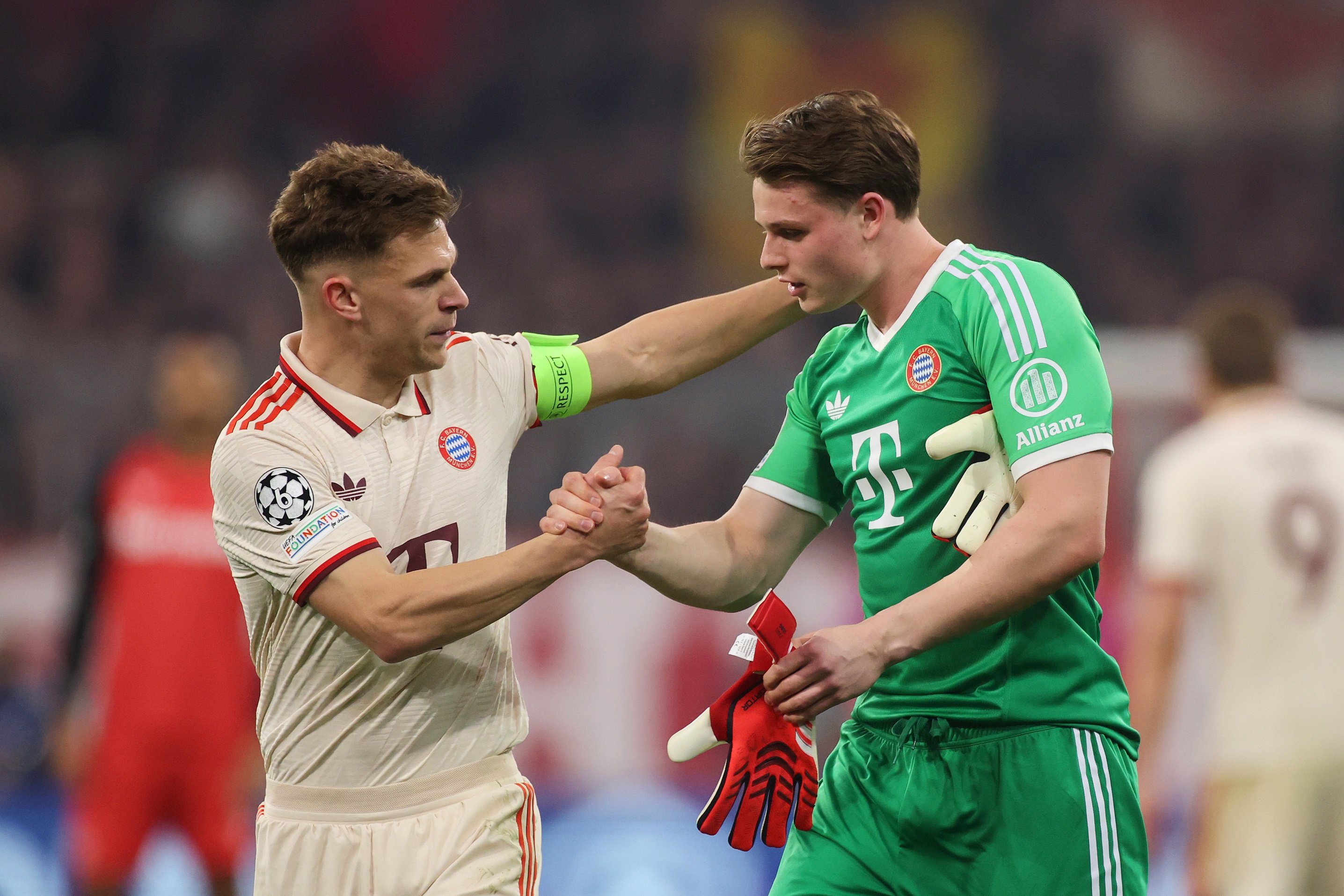 Joshua Kimmich shakes hands with Bayern Munich goalkeeper Jonas Urbig.
