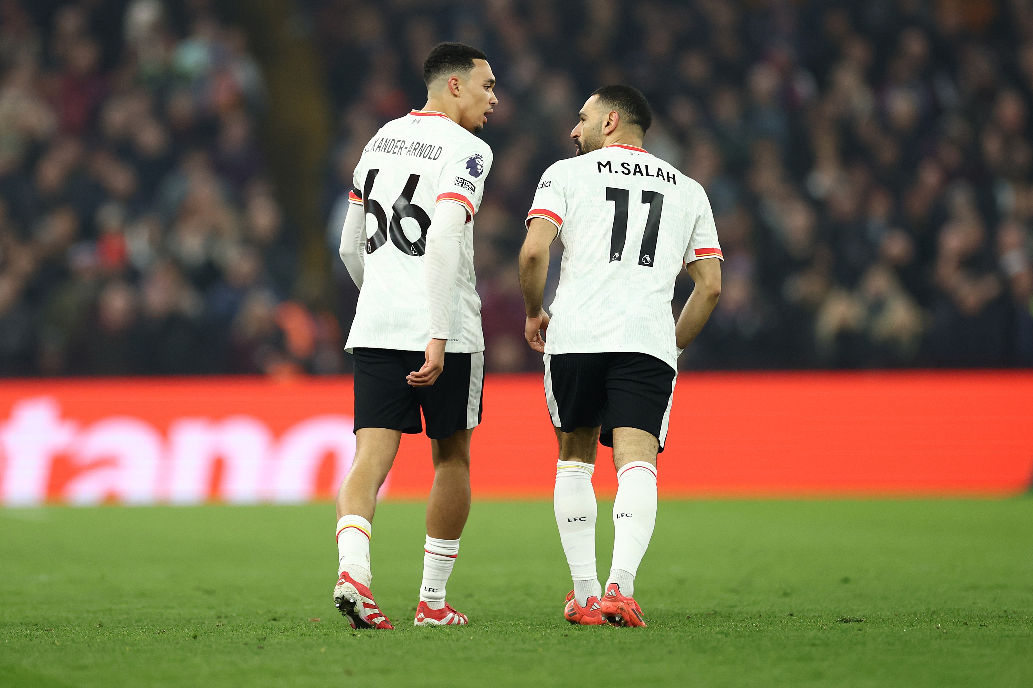 Mo Salah and Trent Alexander-Arnold speak together on the pitch.
