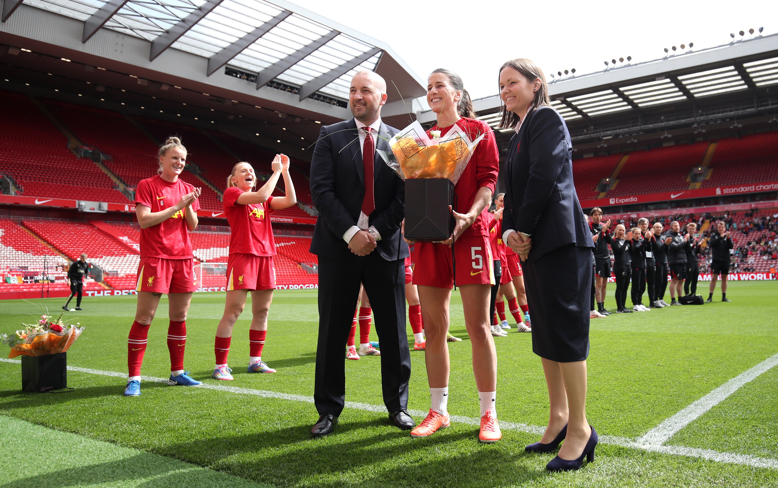 Niamh Fahey holds a bouquet of flowers on the Anfield pitch.