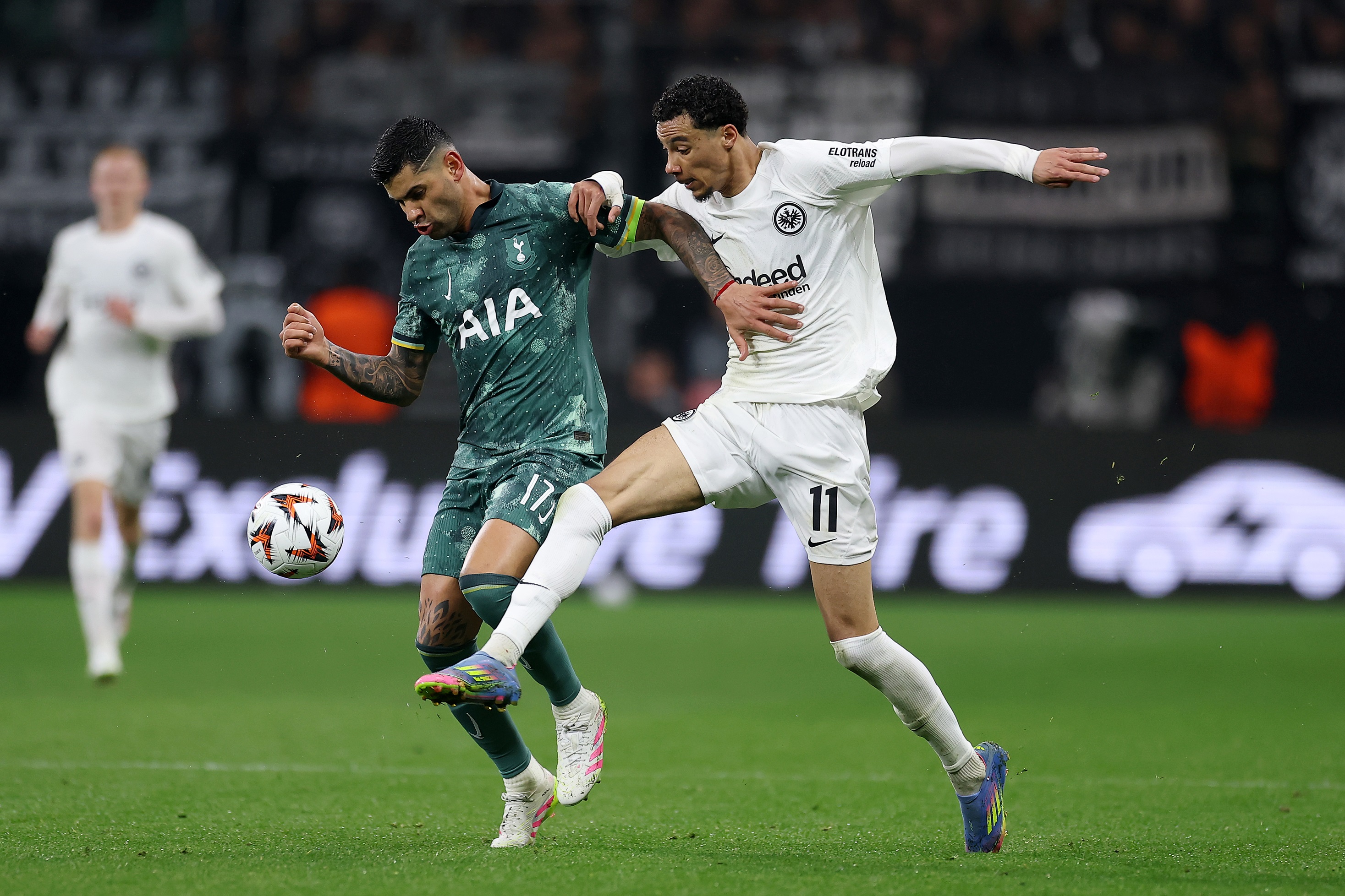 Hugo Ekitike sticks out his leg to challenge Cristian Romero for the ball.