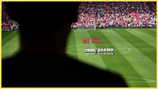Liverpool fan looks on at Liverpool players on the pitch.