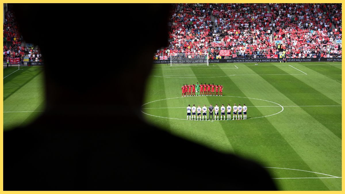 Liverpool fan looks on at Liverpool players on the pitch.