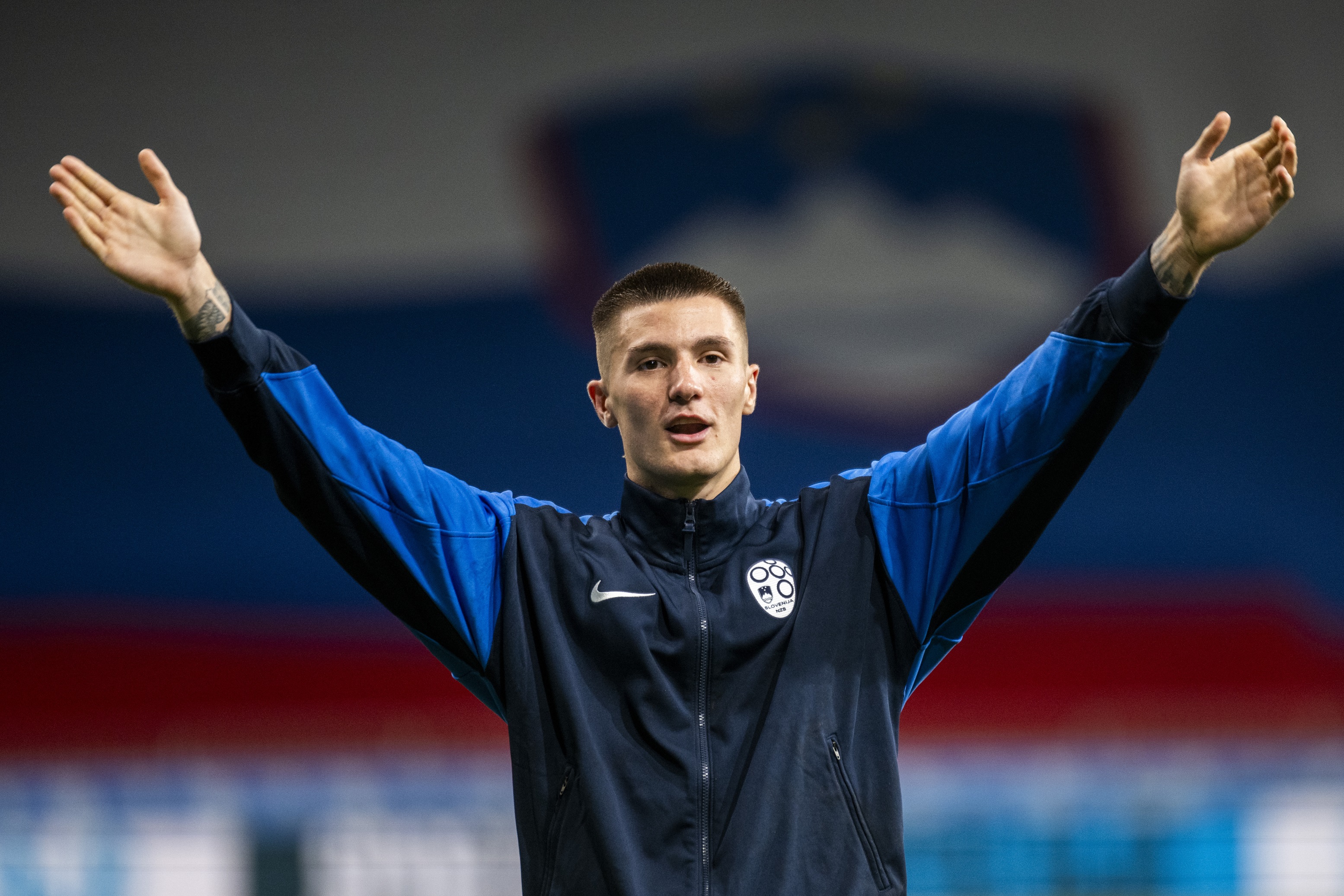 Benjamin Sesko holds his arms up and wide in celebration during Slovenia game.