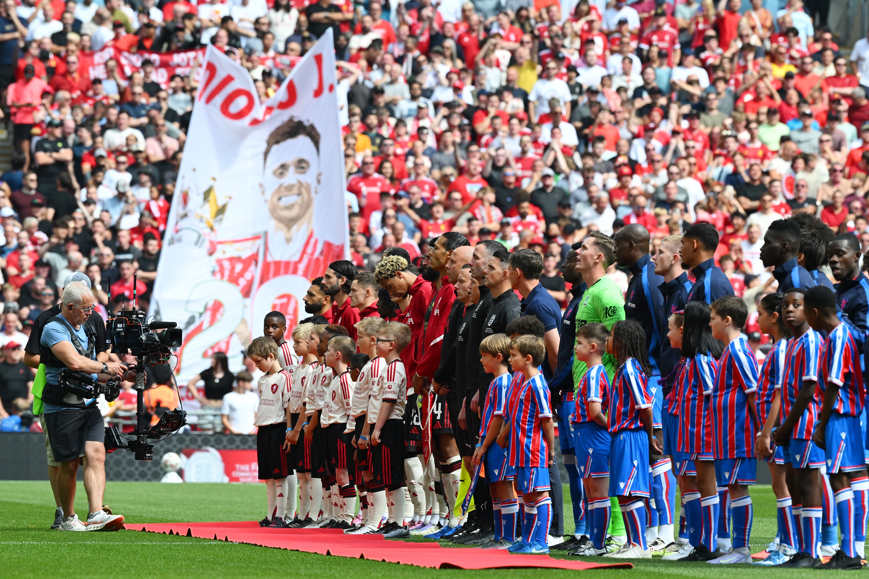 Liverpool and Crystal Palace players line up with Diogo Jota banner in the background.