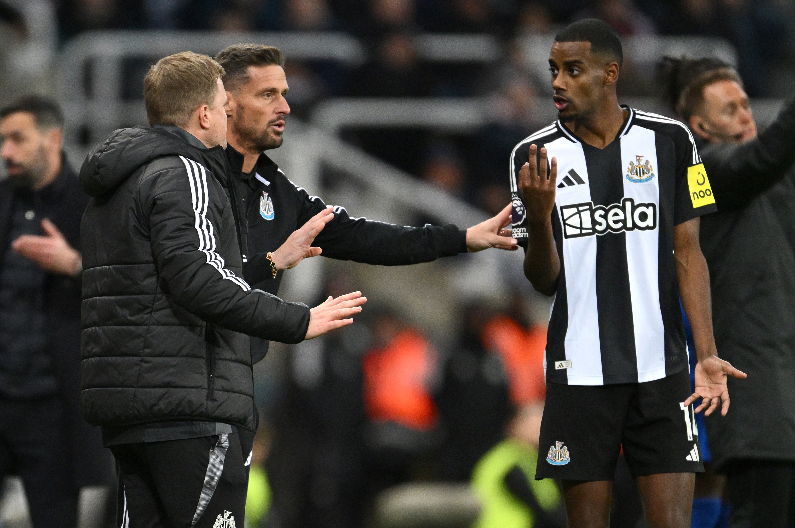 Eddie Howe speaks with Alexander Isak as the Newcastle striker gestures with his hands.
