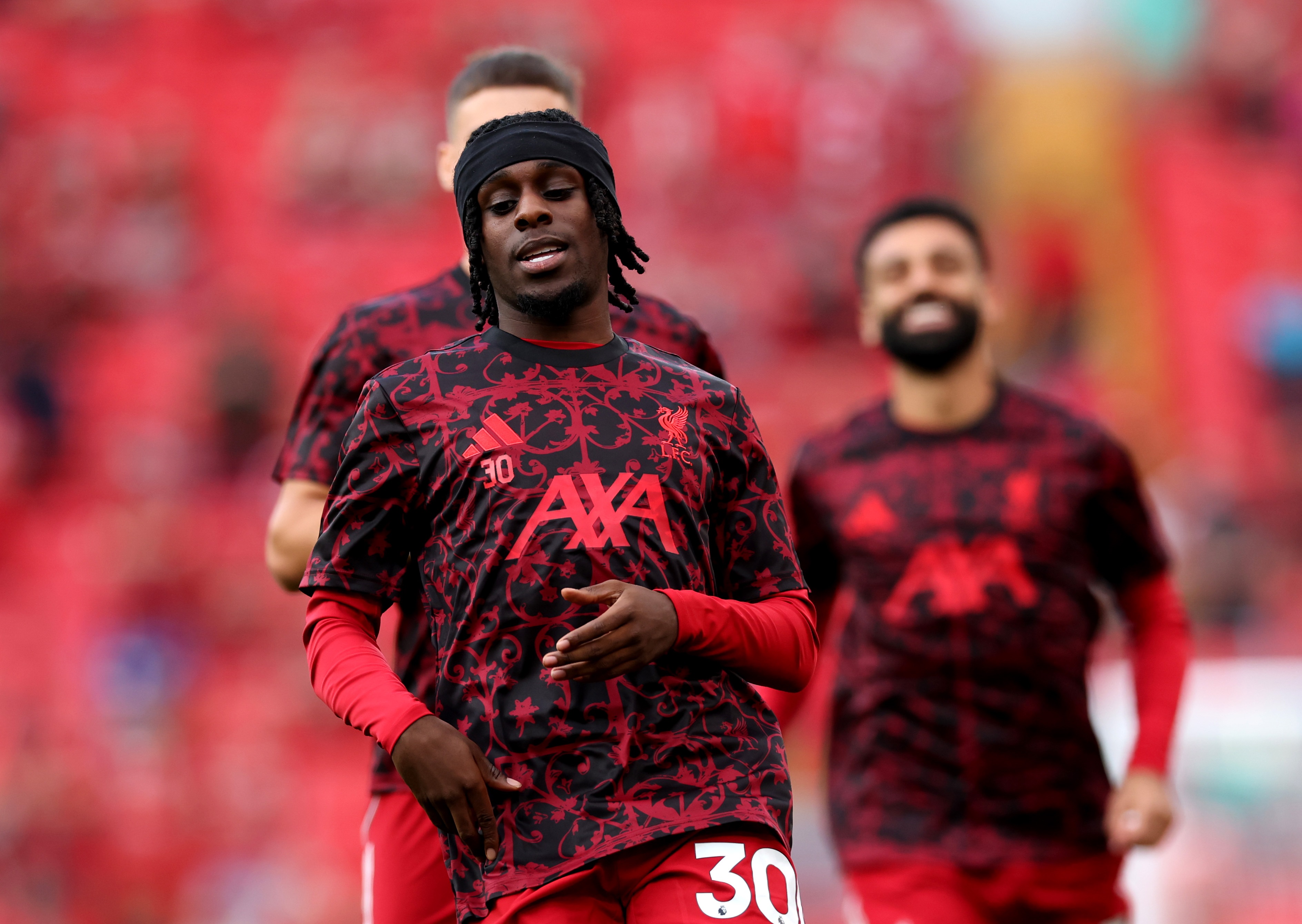 Jeremie Frimpong warms up with Liverpool teammates on the pitch.