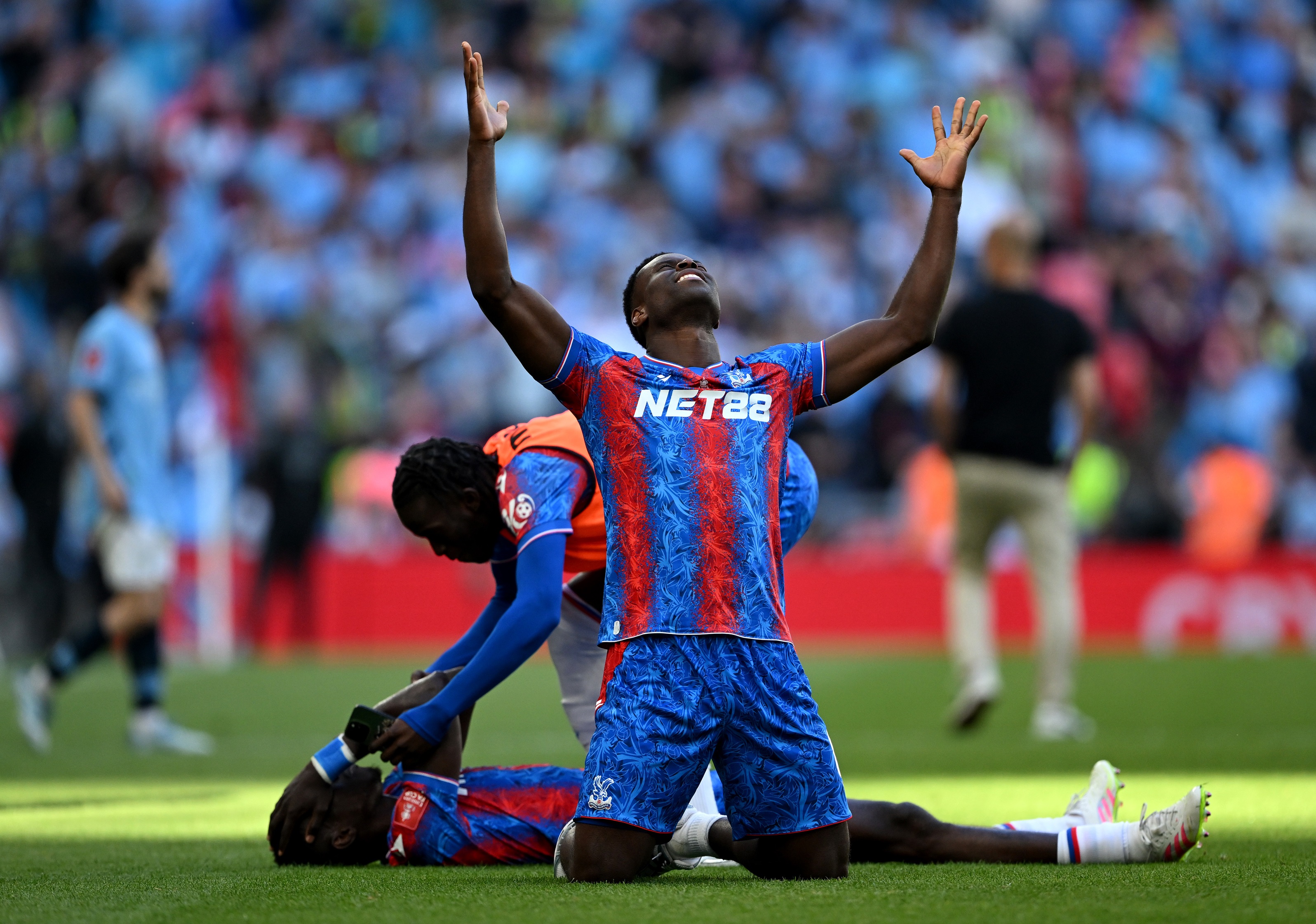 Marc Guehi kneels down with his hands and face bent up to the sky.