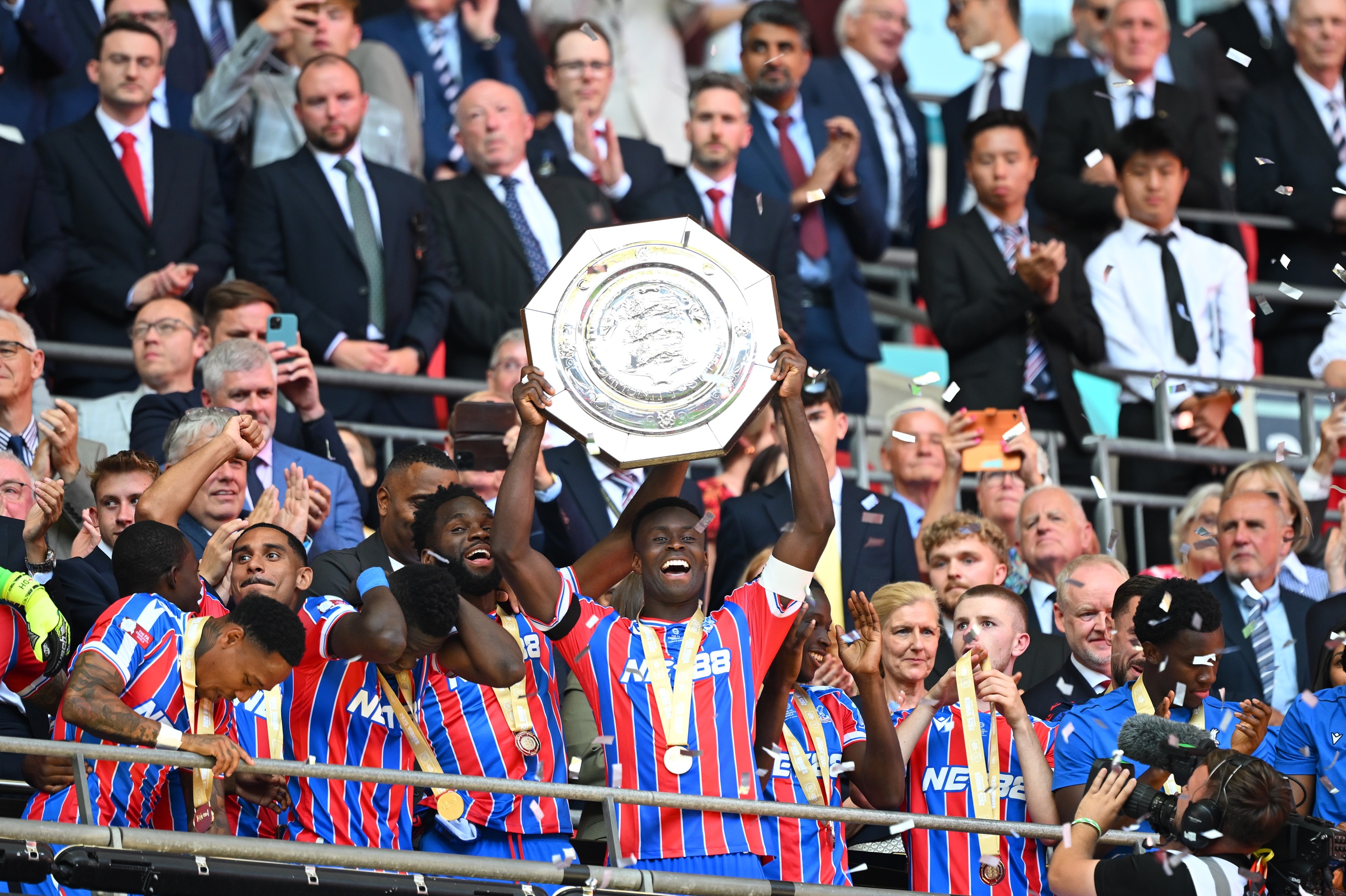 Marc Guehi lifts the Community Shield trophy in front of his Crystal Palace teammates and fans.