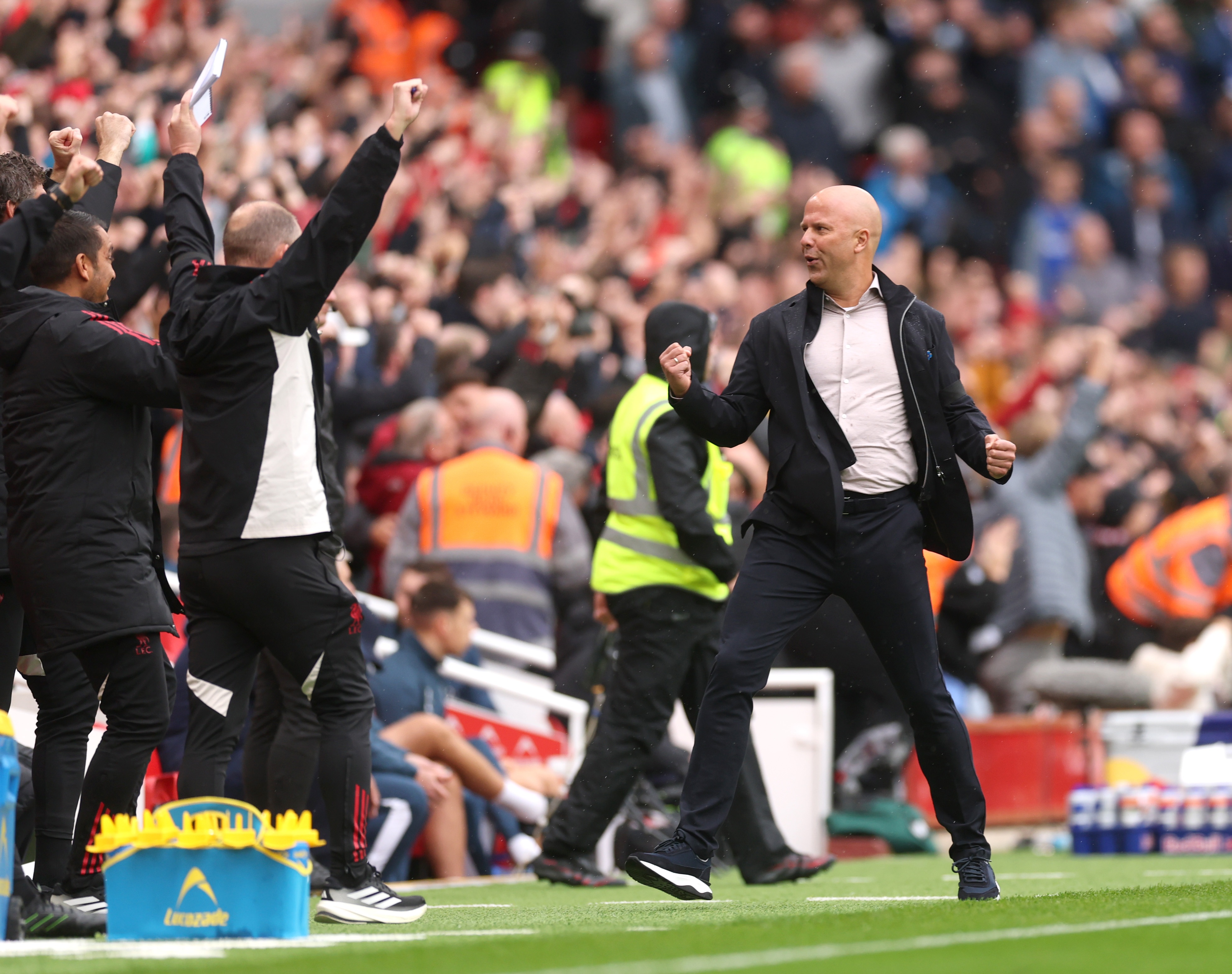 Arne Slot pumps his fist in celebration with Liverpool coaches on the touchline.