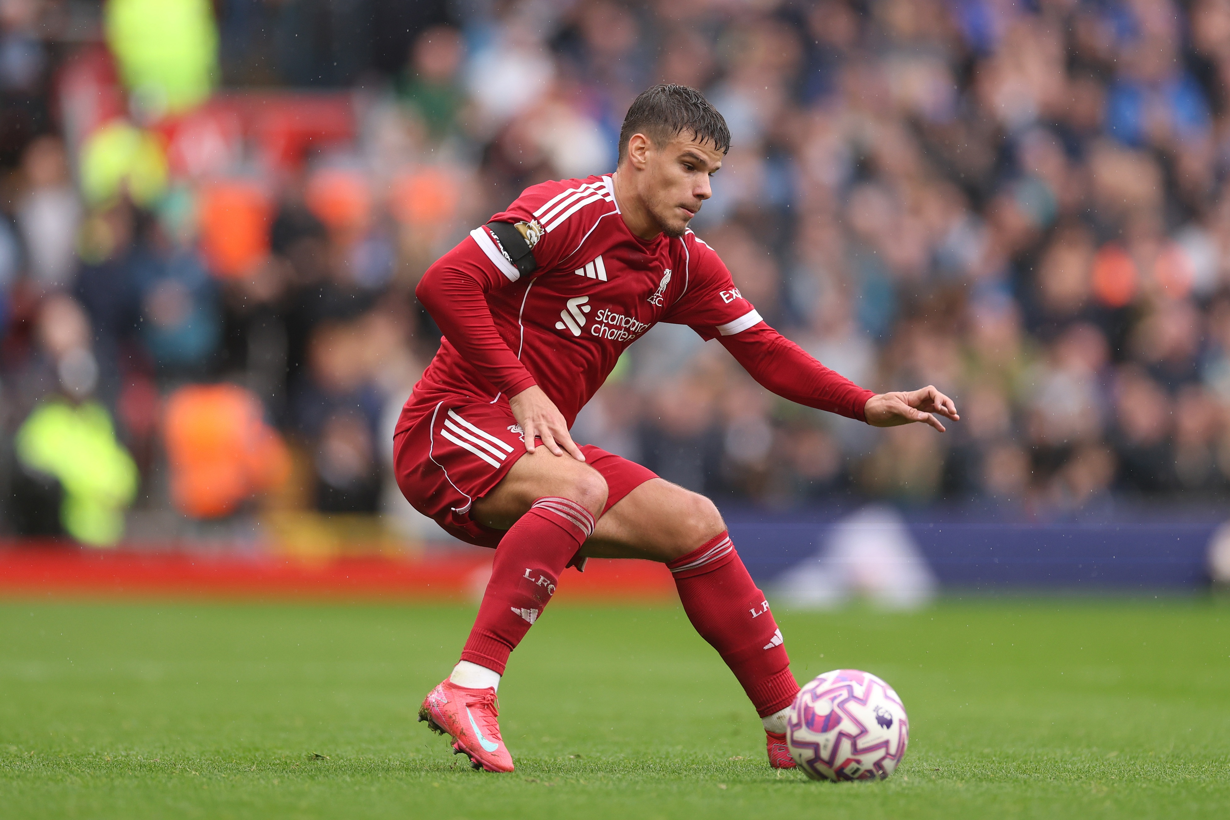 Milos Kerkez is hunched over with the ball at his feet.
