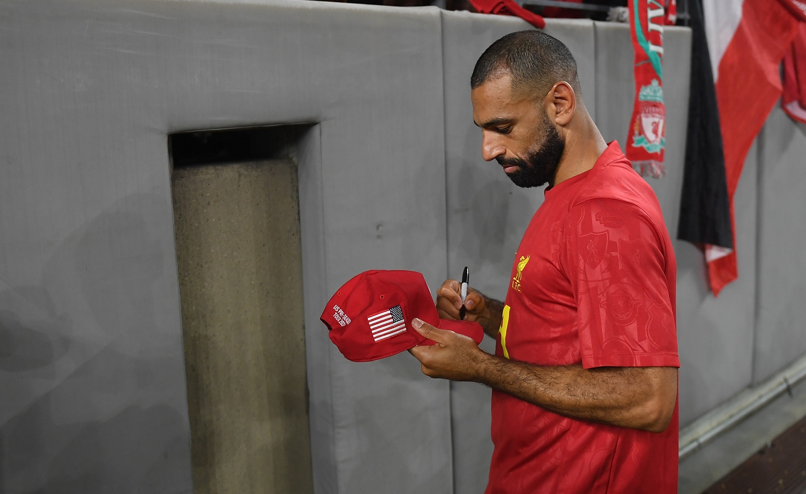 Mo Salah signs a cap for a Liverpool supporter during pre-season