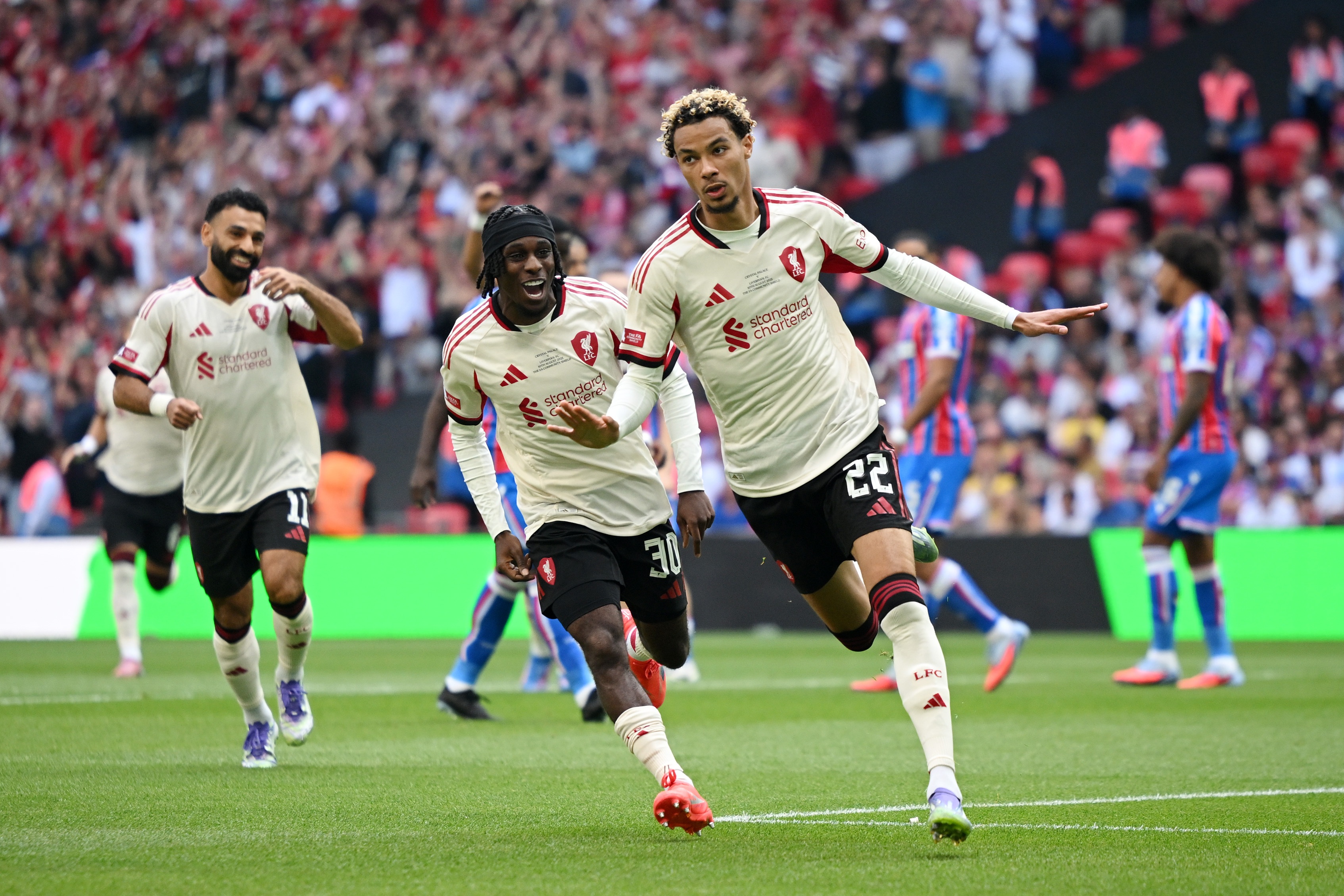 Hugo Ekitike is chased by Jeremie Frimpong and Mo Salah after scoring a goal.