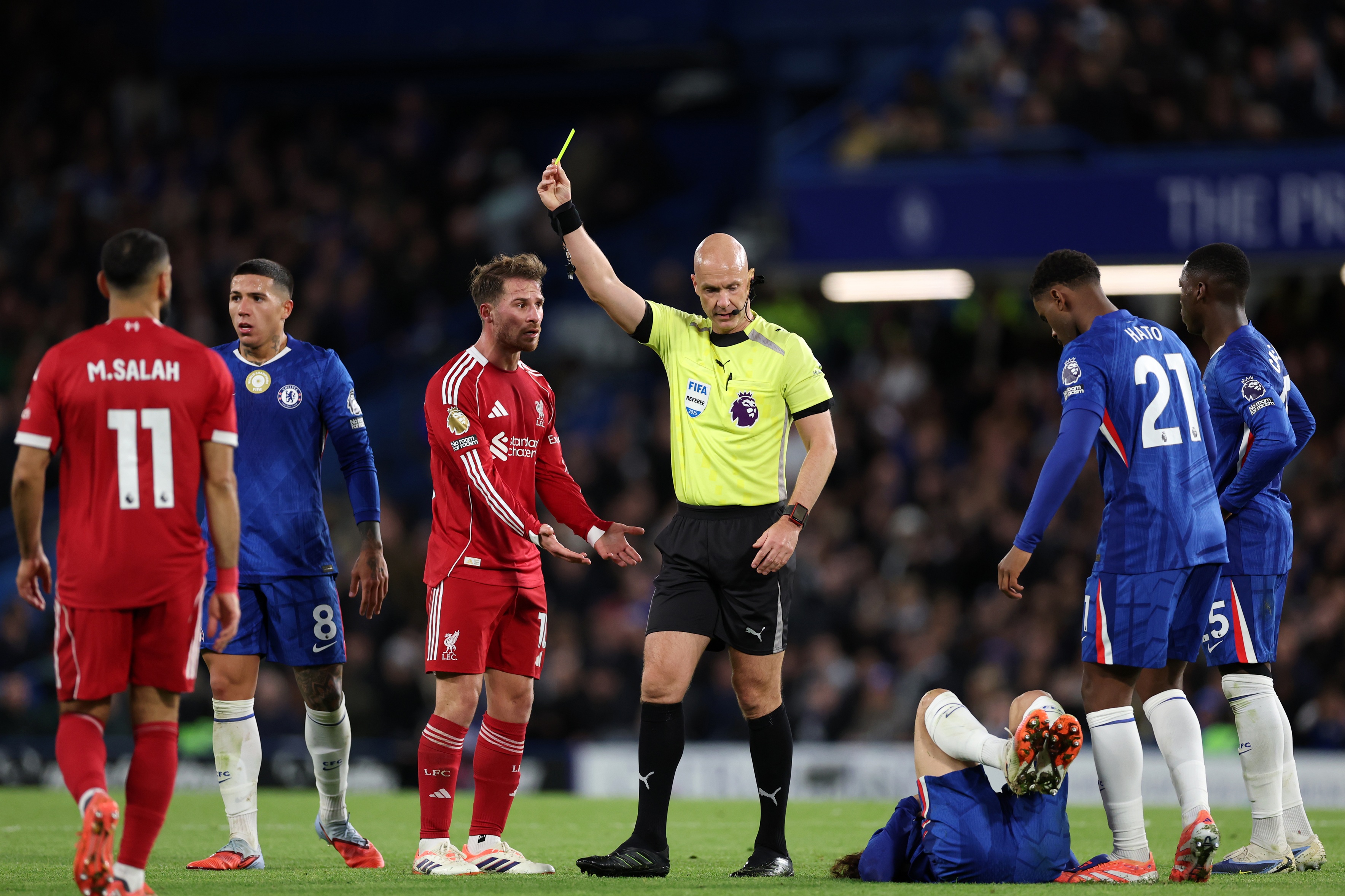 Anthony Taylor shows Liverpool midfielder Alexis Mac Allister a yellow card.