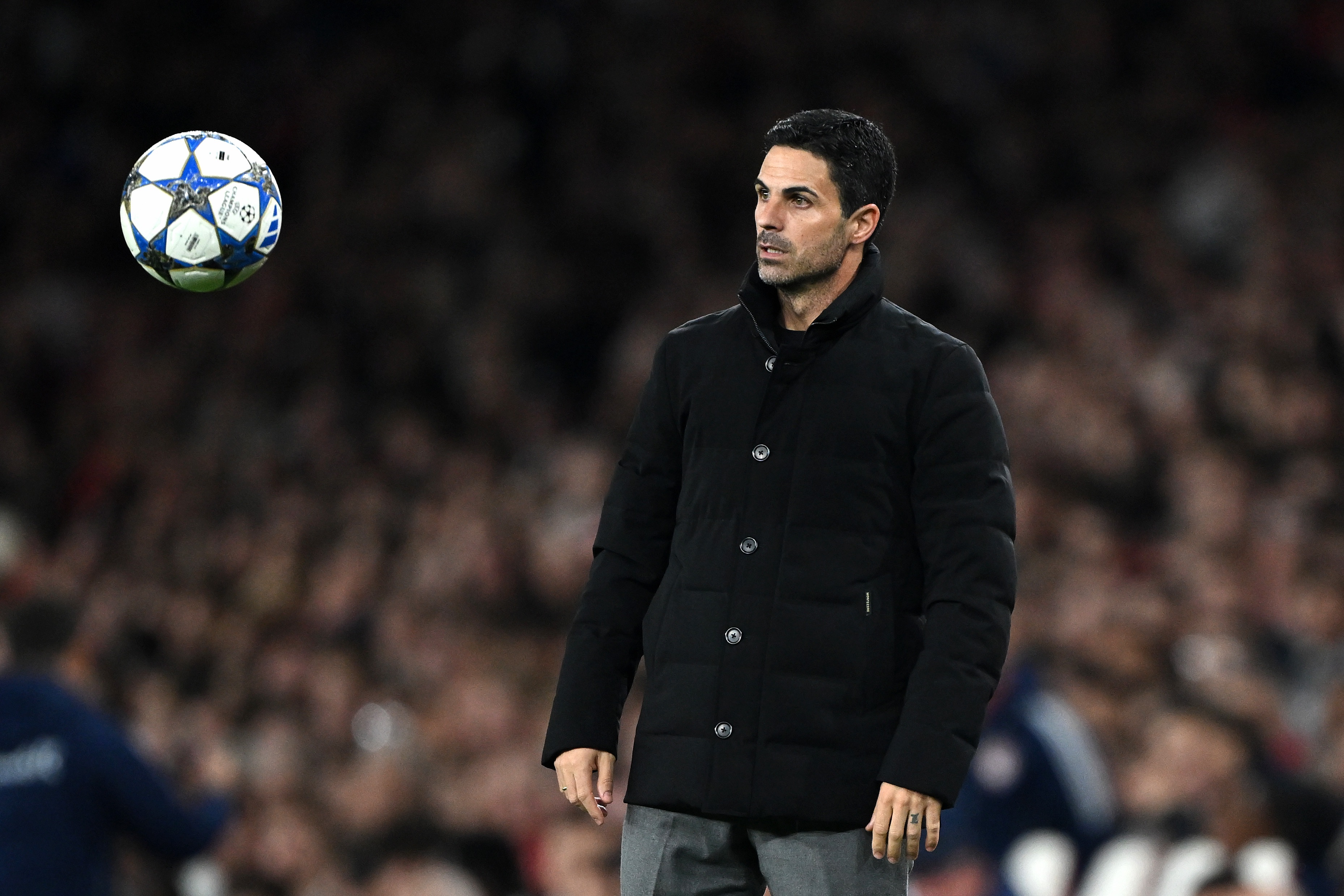 Mikel Arteta stands on the touchline watching a flying football.