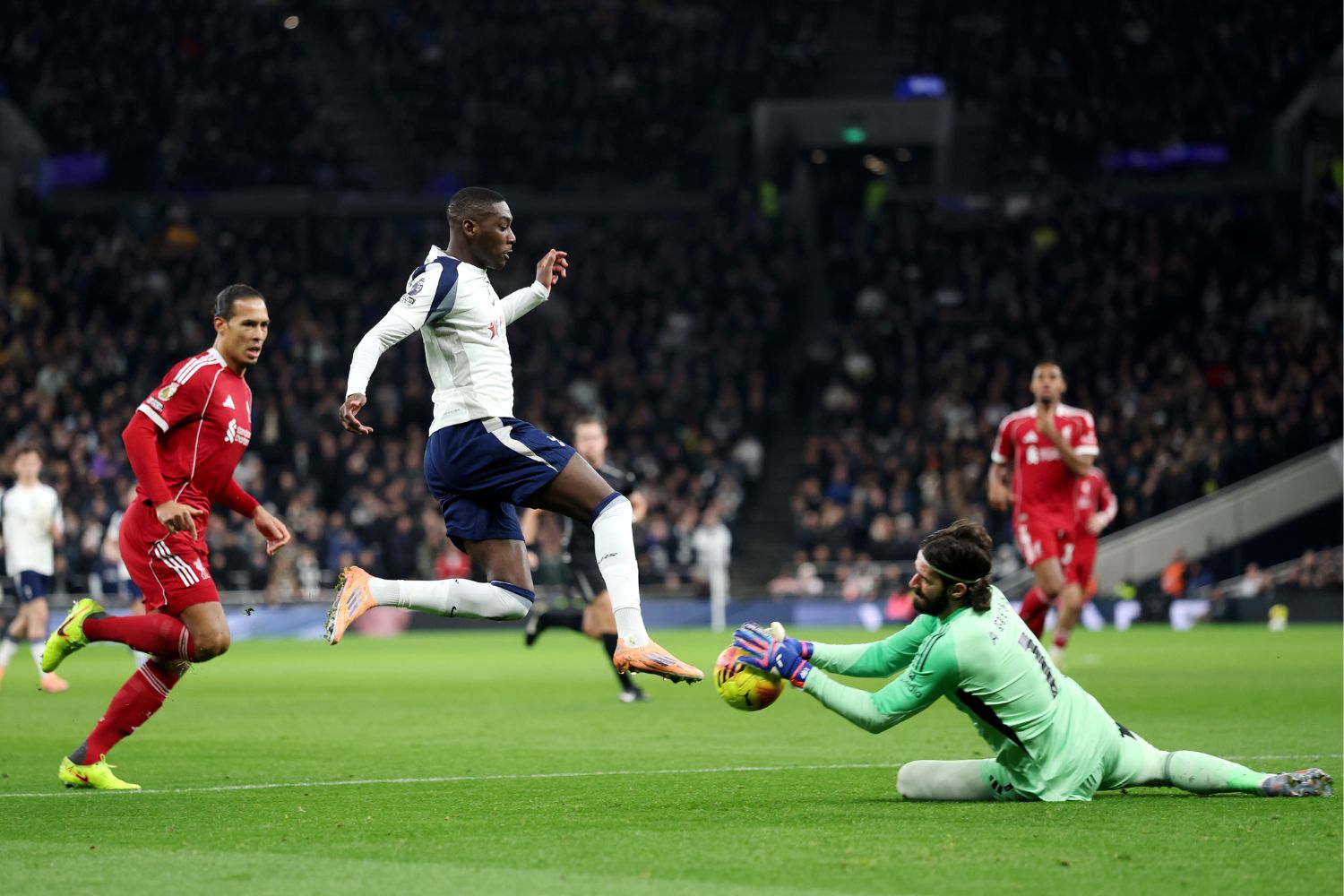 Alisson Becker of Liverpool gathers the ball whilst under pressure from Randal Kolo Muani of Tottenham
