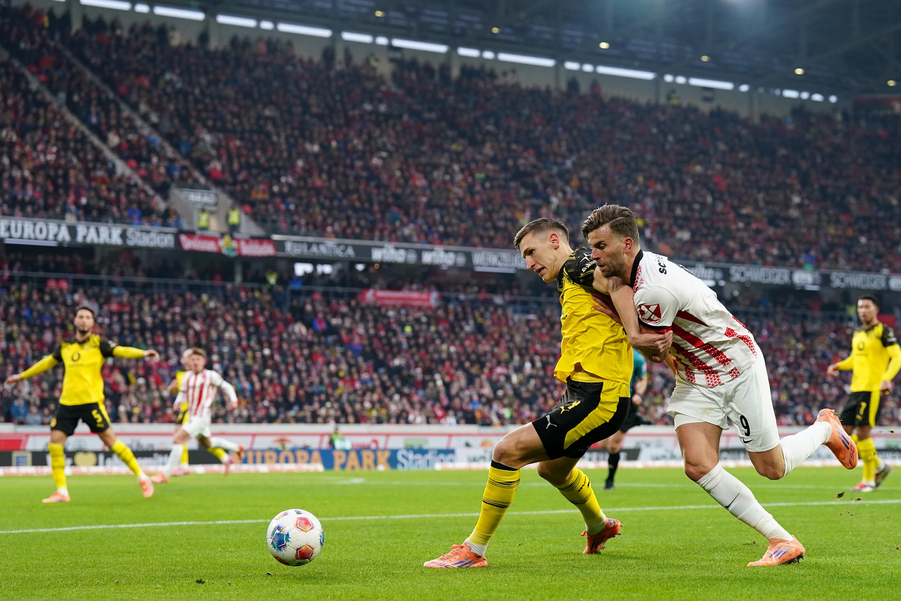 Nico Schlotterbeck holds off a Freiburg player competing for the ball.