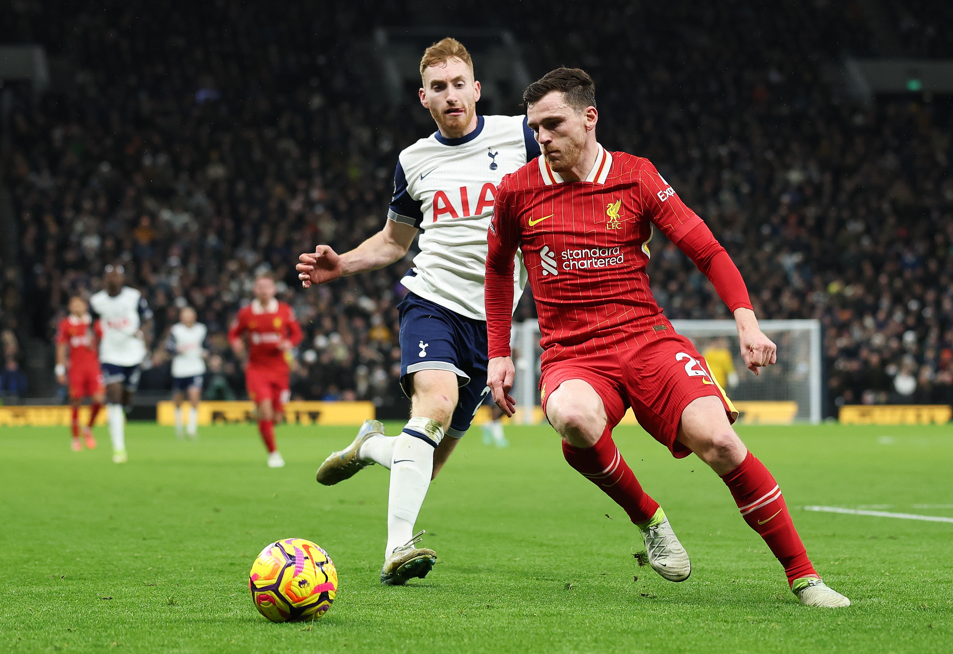 Andy Robertson dribbles with the ball against a Tottenham player.