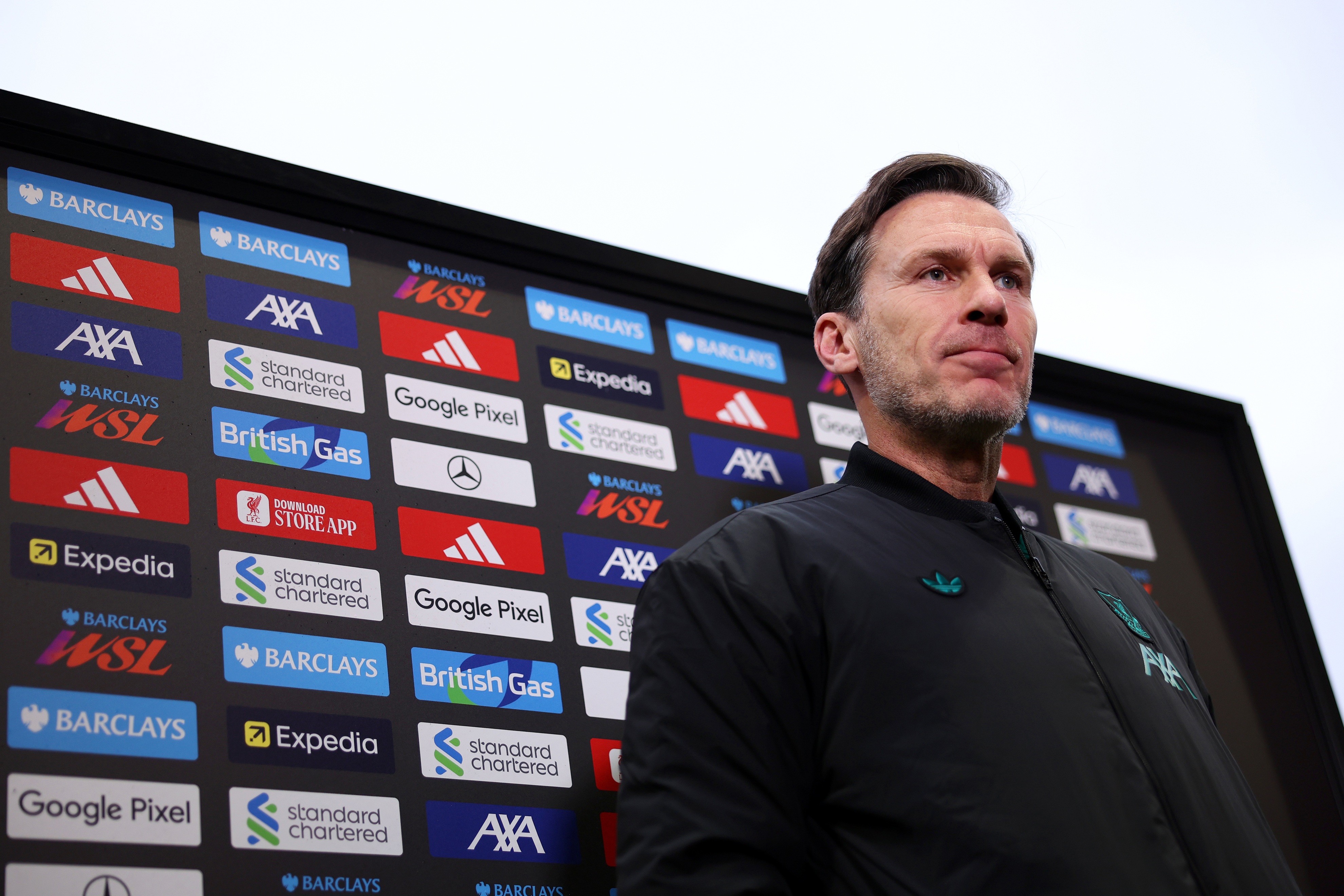 Liverpool Women's head coach Gareth Taylor stands in front of an advertising wall.