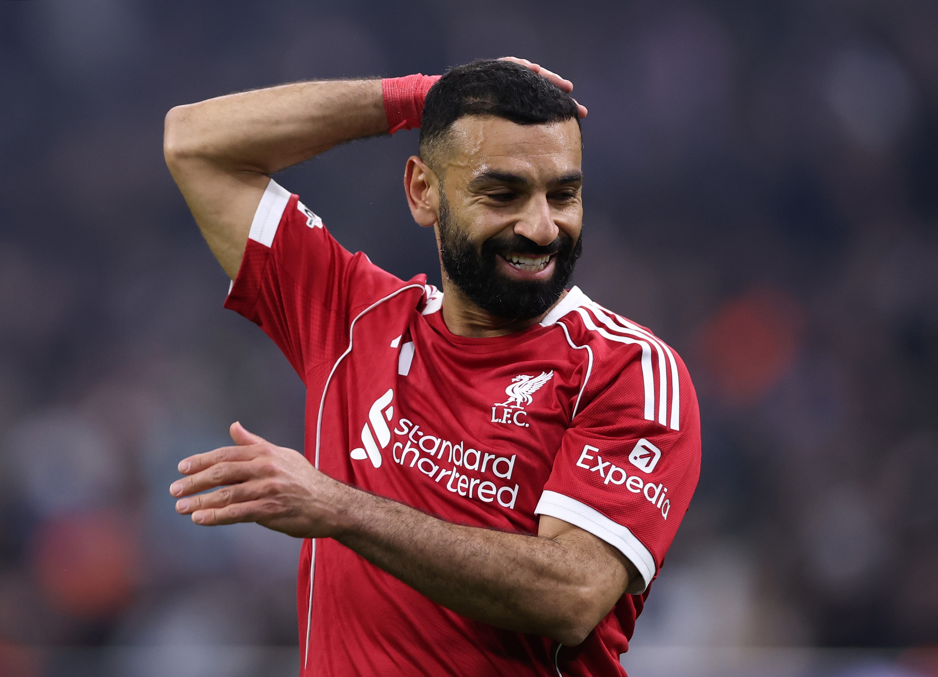 Mo Salah reacts throwing up an arm behind his head.