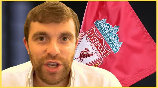 Fabrizio Romano speaks in front of a Liverpool flag.