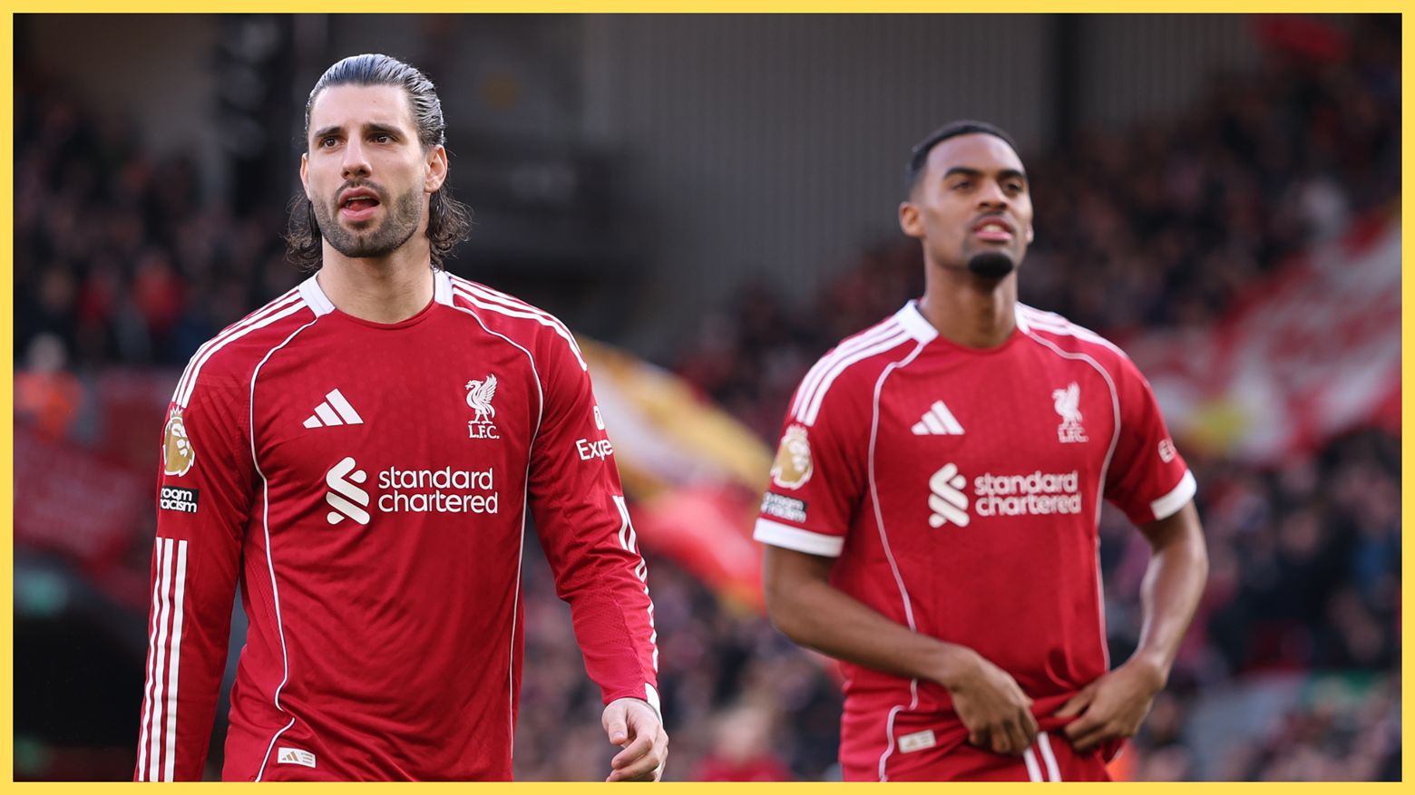 Liverpool midfielders Dominik Szoboszlai and Ryan Gravenberch walk on the pitch during Premier League game.