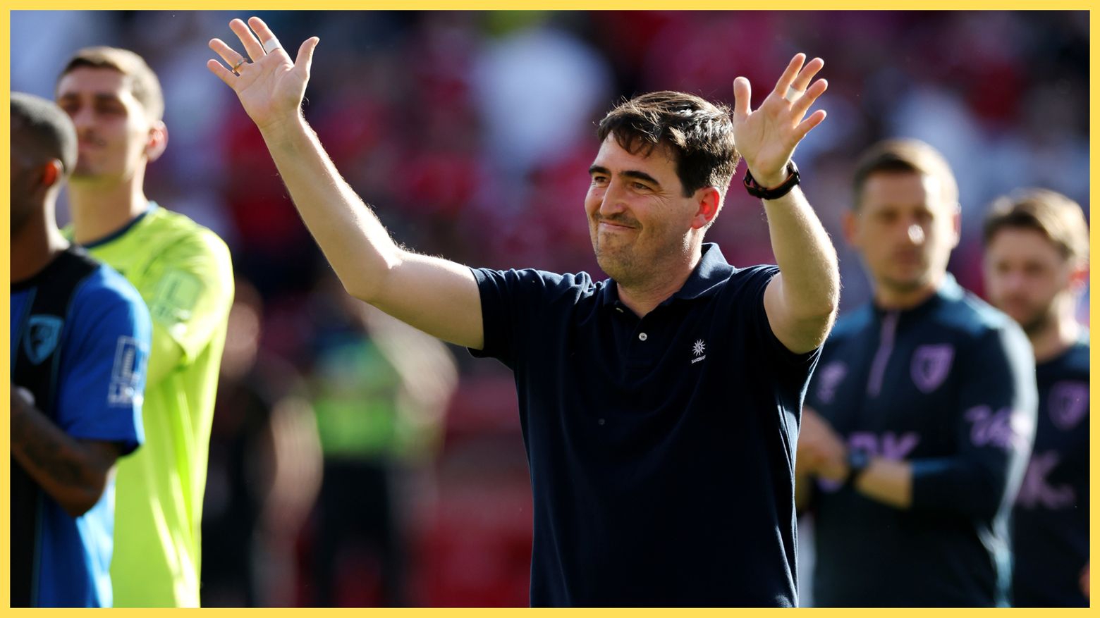 Liverpool manager Andoni Iraola throws his arms up in the air in celebration.