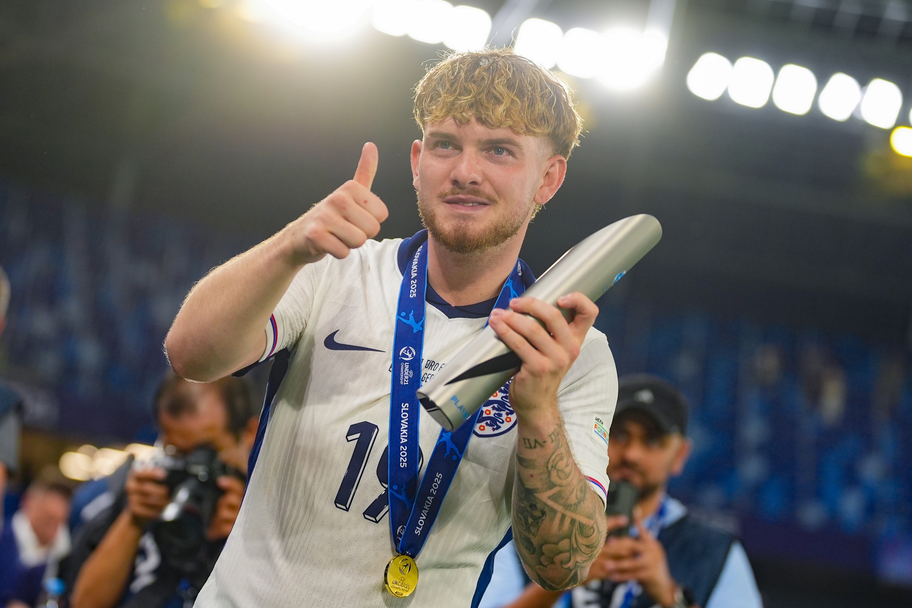 England player Harvey Elliott gives a thumbs-up gesture and holds a silver award in his left hand.