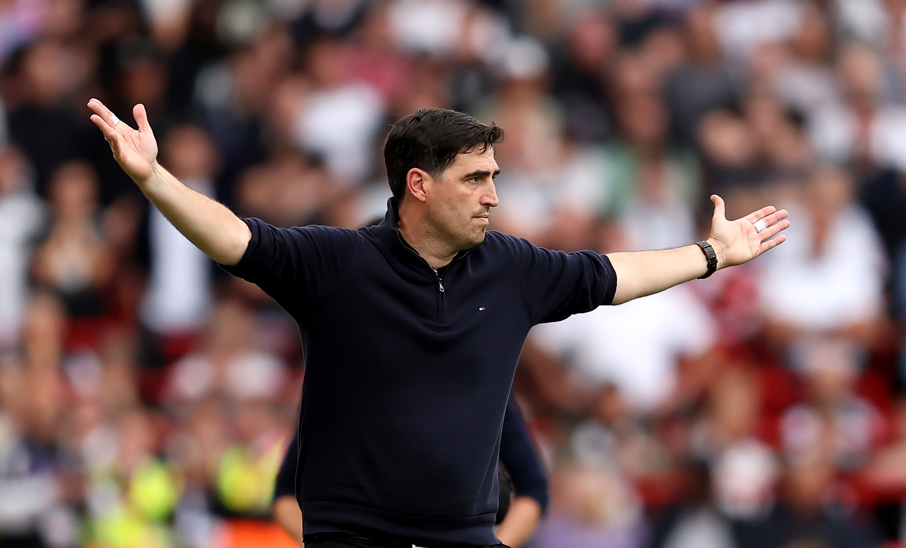 Liverpool manager Andoni Iraola holds his arms out wide in frustration.