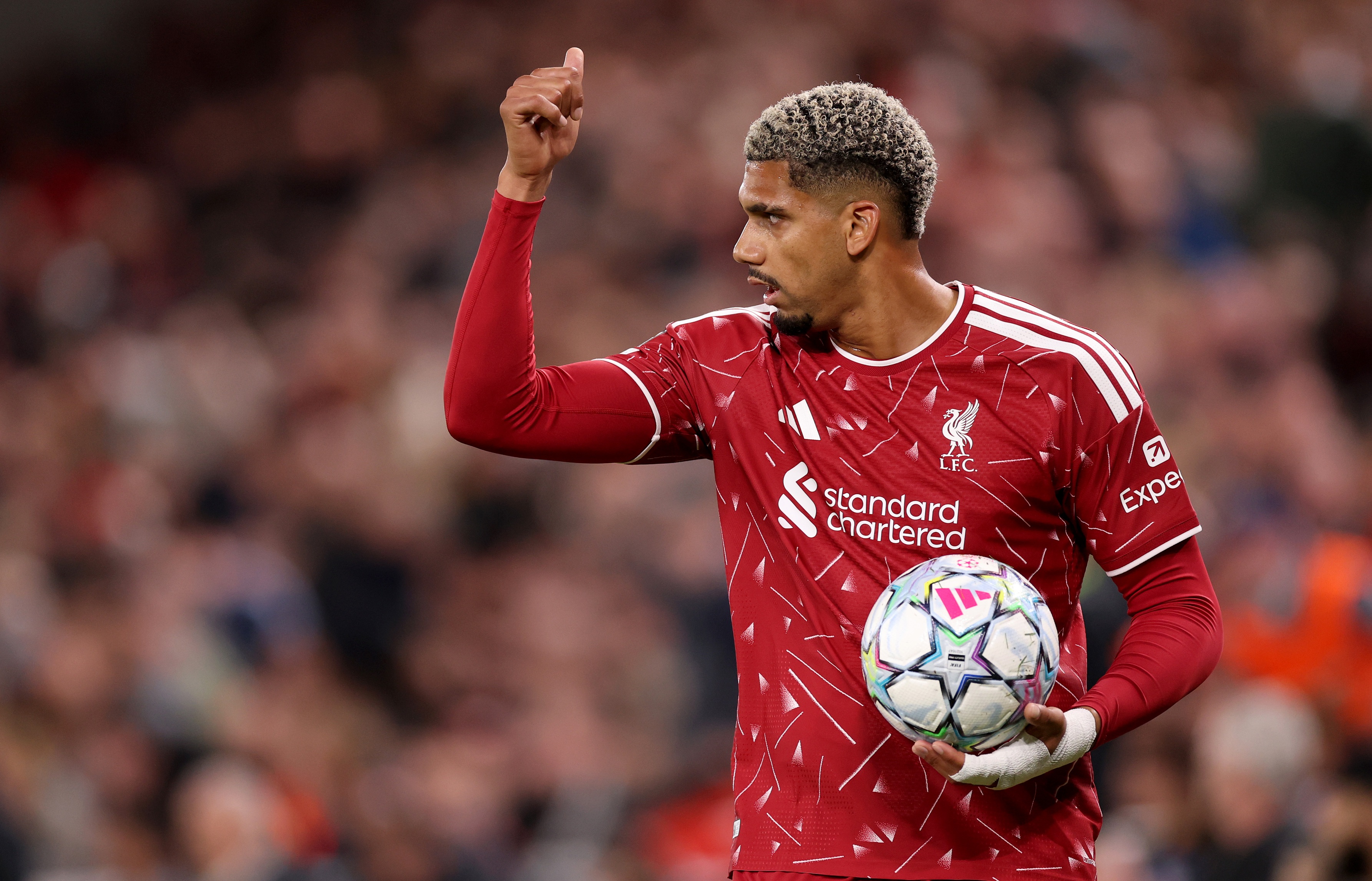 Liverpool defender Ronald Araujo gives a thumbs-up expression while holding the football in his left hand.