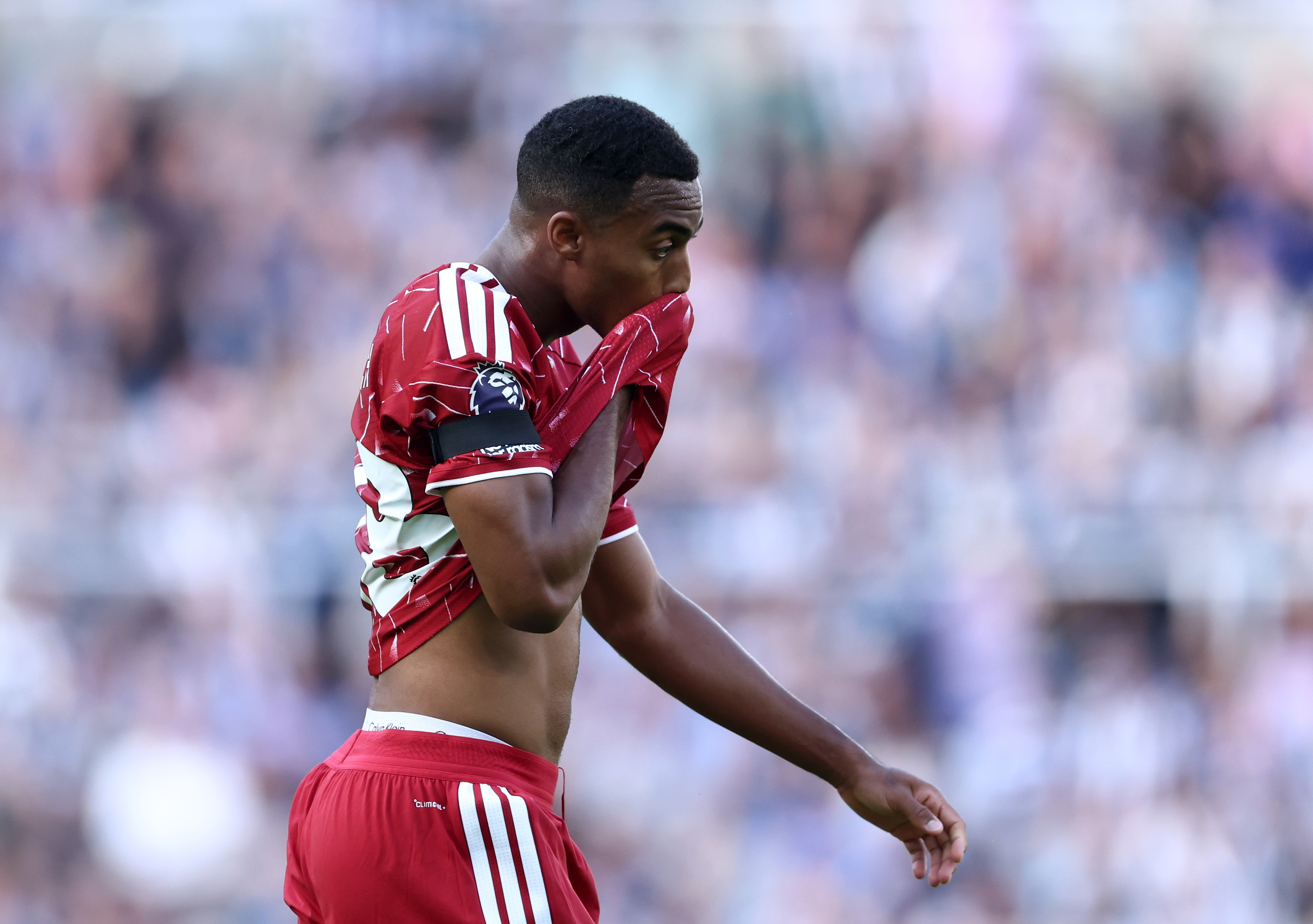 Ryan Gravenberch wipes his face with the bottom half of his Liverpool shirt.